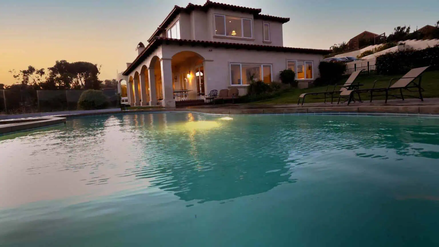 Outdoor pool beside the hillside residence at sunset