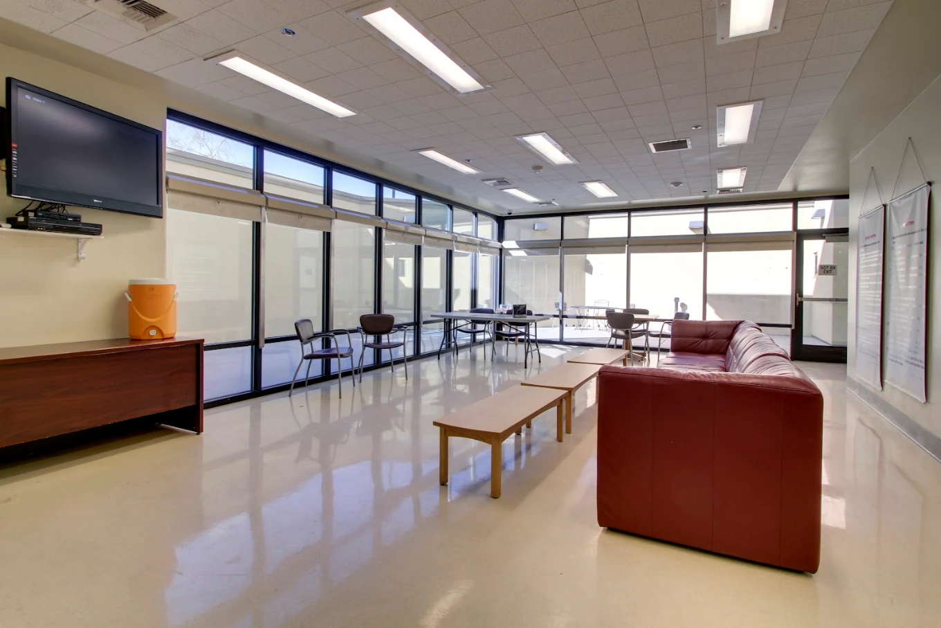 Waiting area with a TV, tables and chairs.