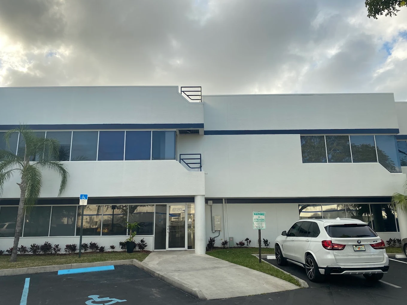 Exterior of a white two-story treatment center building with accessible parking and palm trees