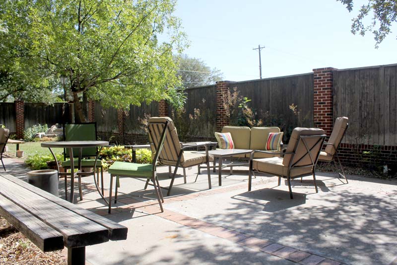 Outdoor courtyard with seating and tables surrounded by greenery
