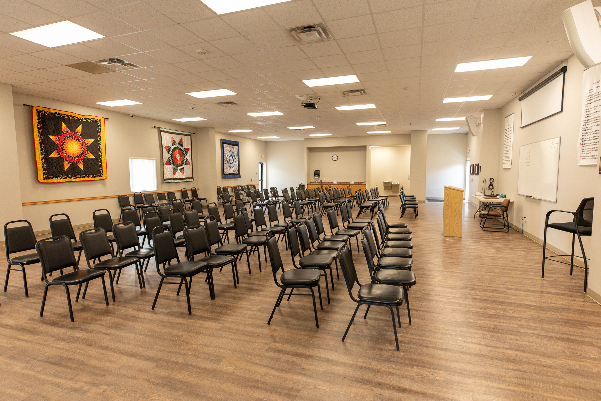 Meeting area with chairs and colorful quilts on the walls