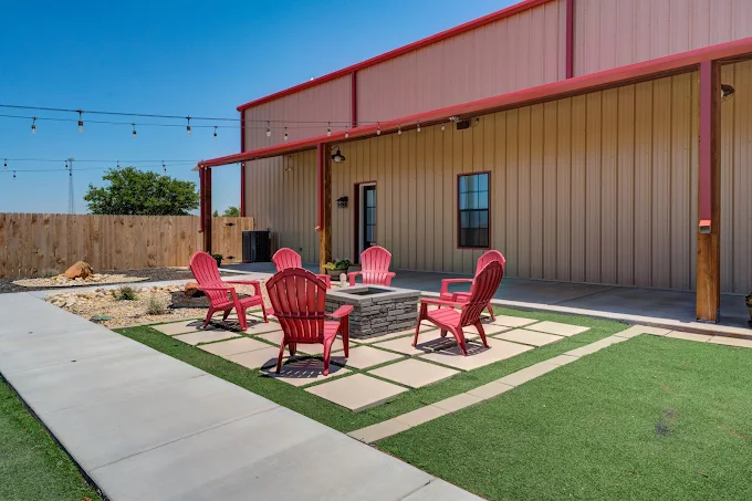 Outdoor fire pit with Adirondack chairs and turf lawn