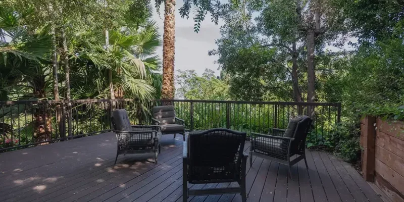 A serene outdoor deck surrounded by lush greenery, featuring cozy seating arrangements perfect for relaxation and enjoying nature.