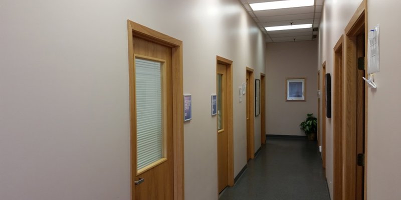 A clean, well-lit hallway with office doors leading to various rooms, creating a professional and welcoming environment for clients.