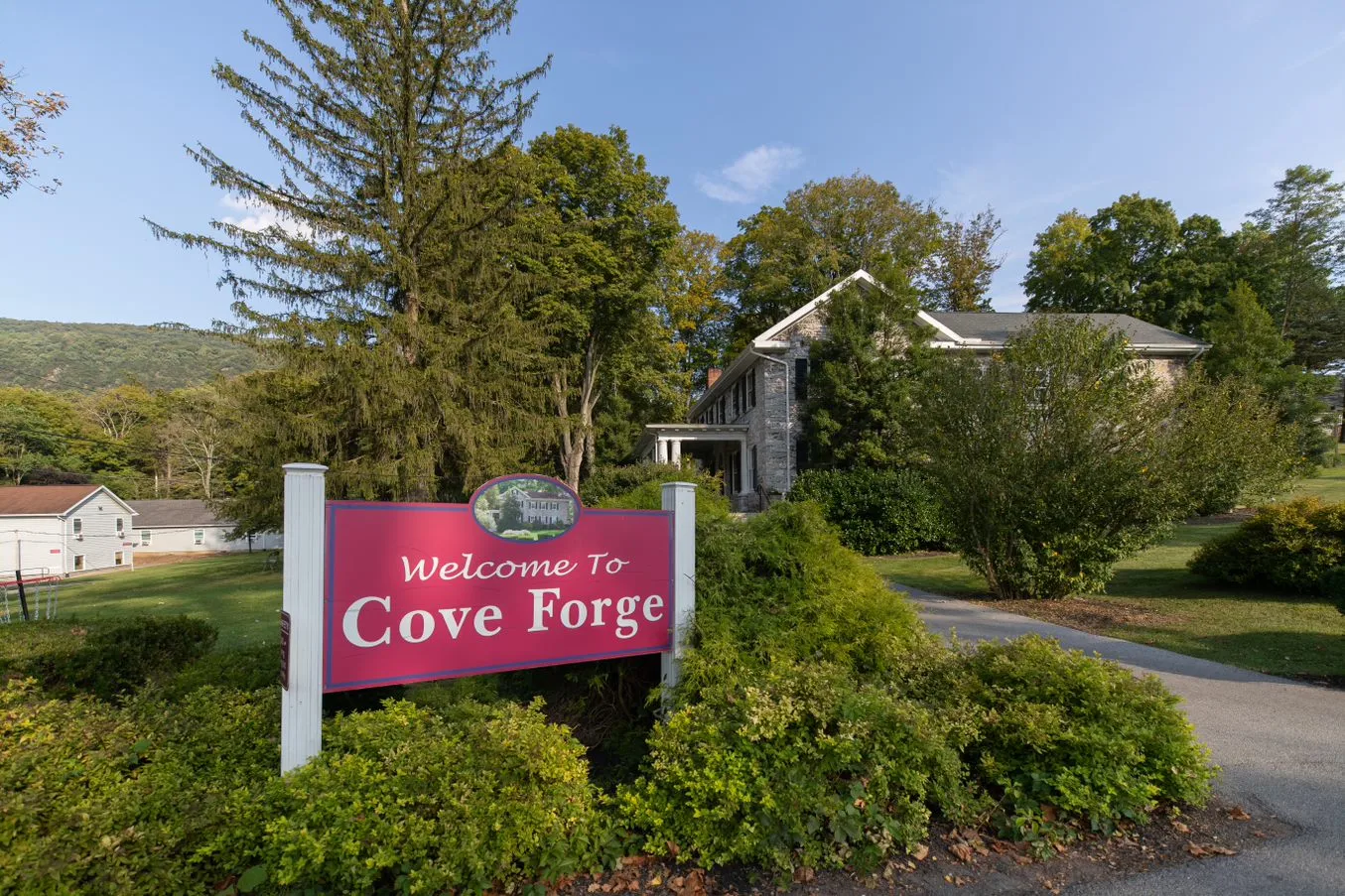 Cove Forge welcome sign with stone building and trees