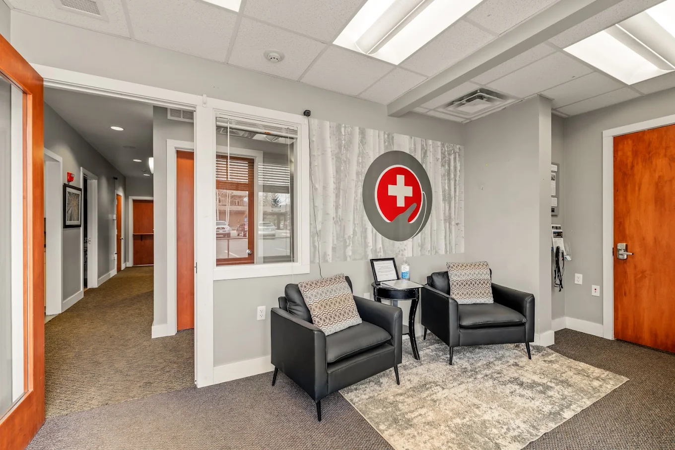 Waiting area with two black armchairs, patterned pillows, area rug, and Foundry wall emblem