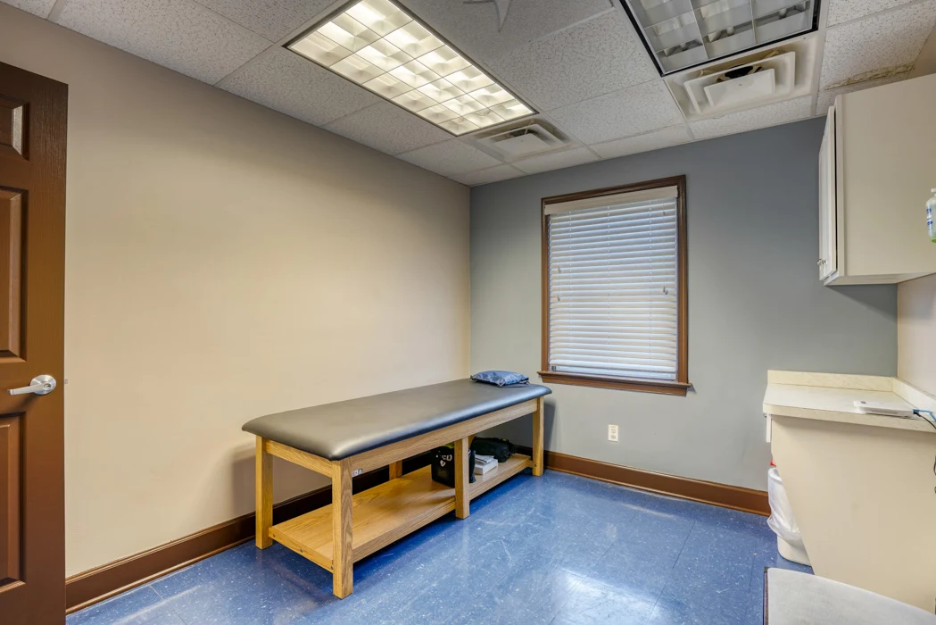 BrightView Health exam room with padded examination table, cabinets, sink, window, and blue flooring
