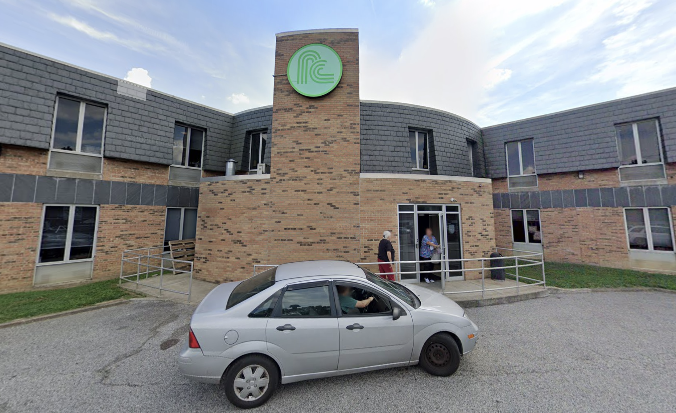Brick Prestera Center building with entrance ramp and parking area