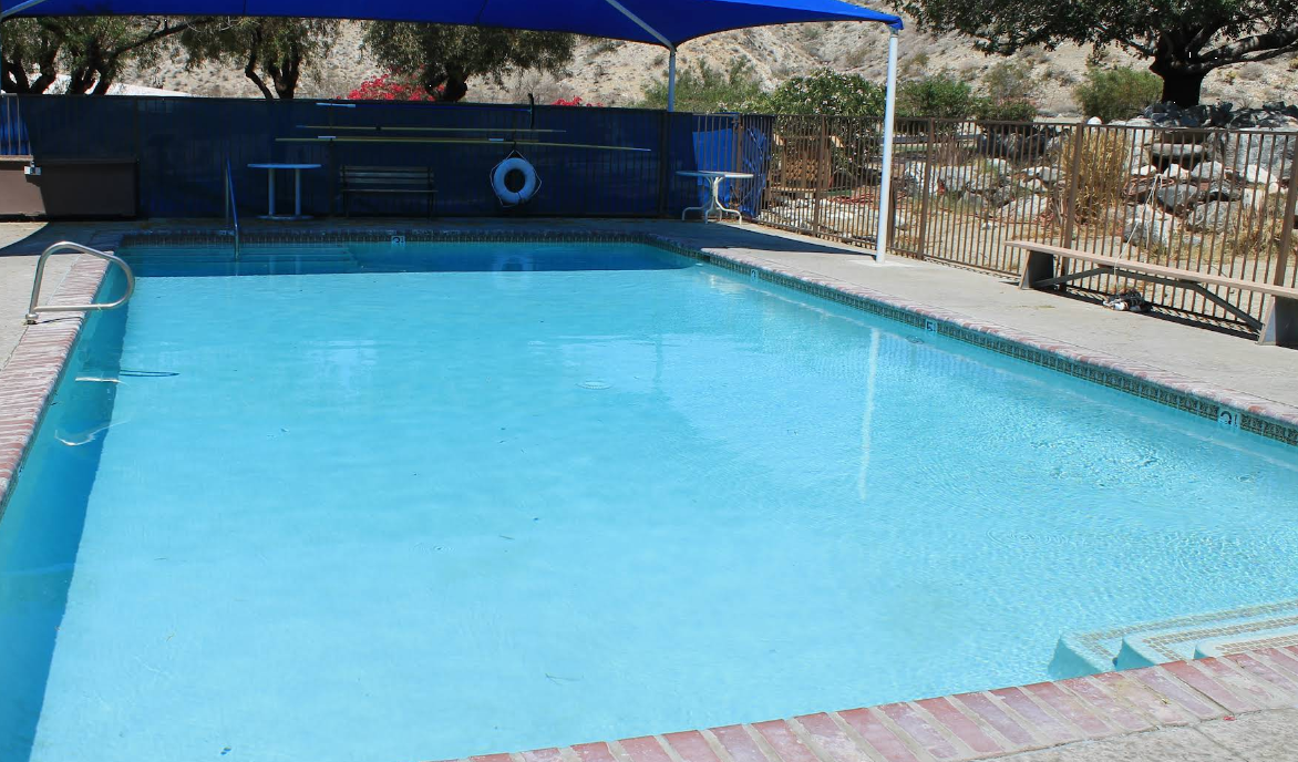 Outdoor swimming pool with shaded seating and desert landscape