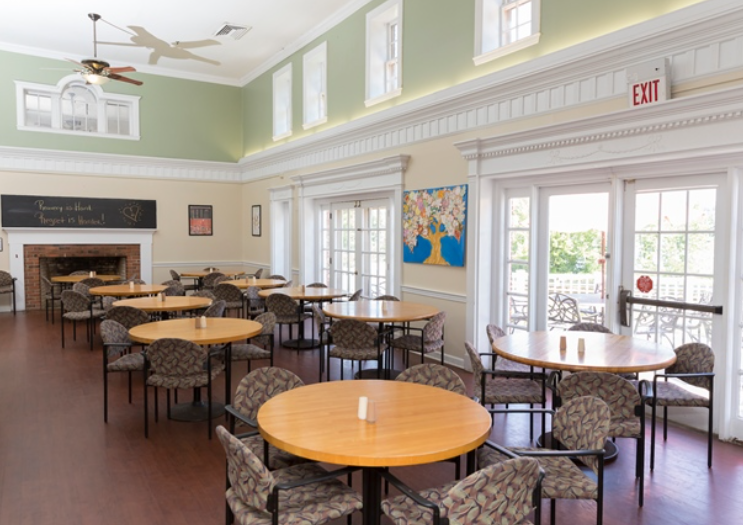 Spacious dining hall with round tables and fireplace