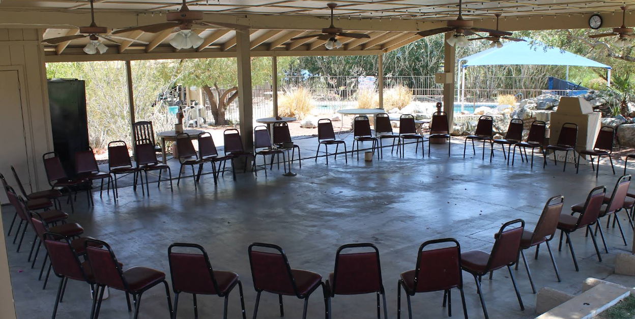 Covered outdoor meeting area with chairs arranged in a large circl