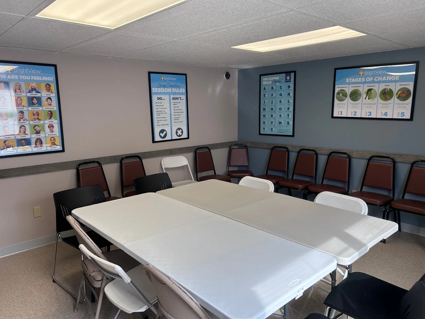 Group therapy room with tables, chairs, and educational posters