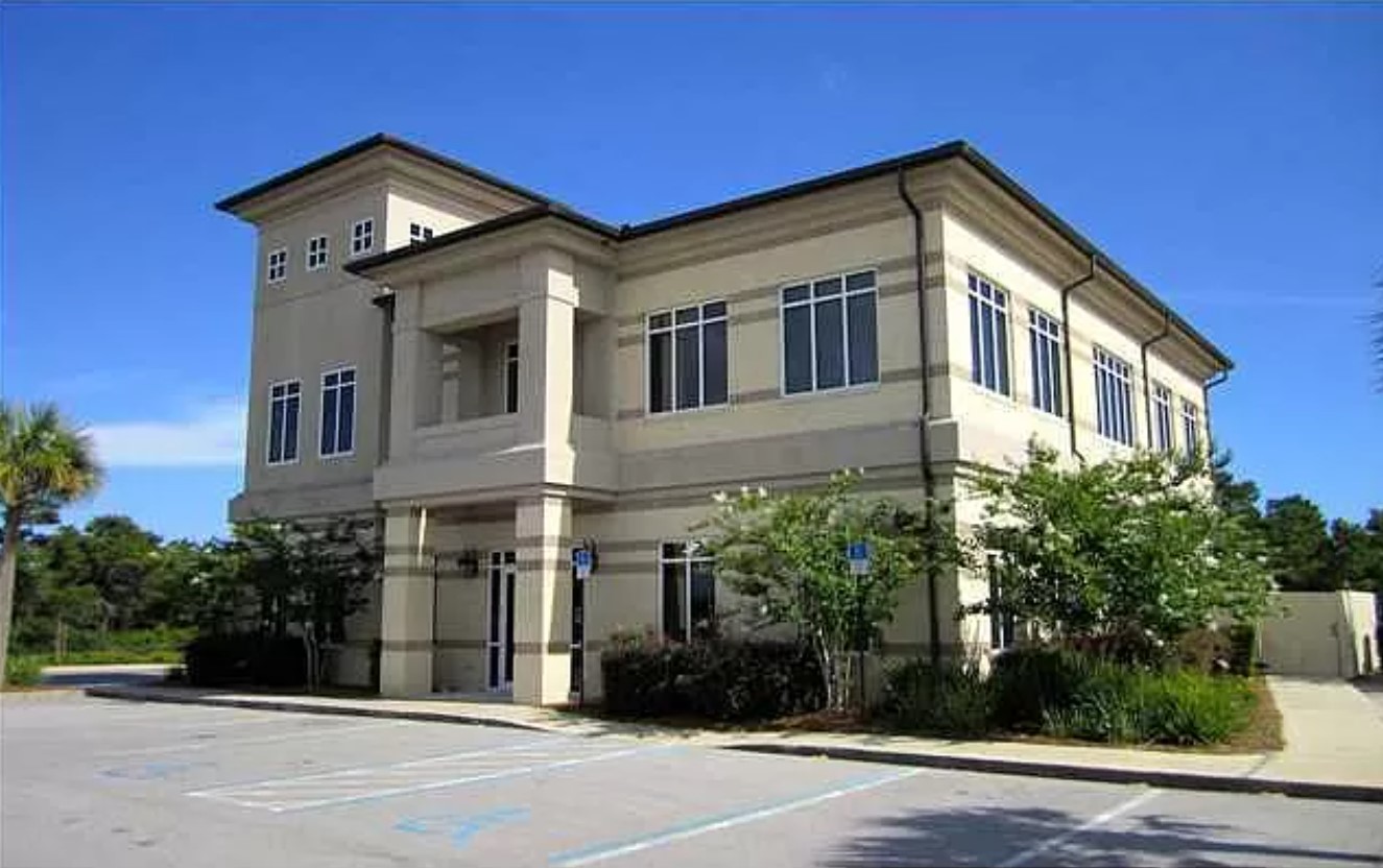 Three-story building with palm trees and balconies