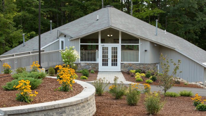 Exterior of a residential recovery facility with a landscaped front yard and flower beds in Canterbury