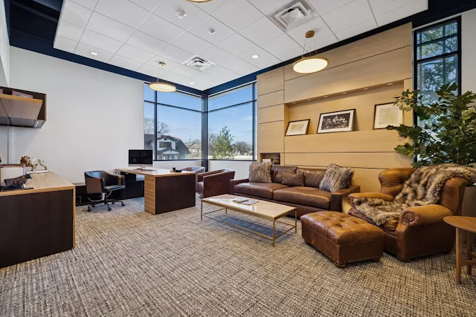 Office lounge with a large leather sofa and patterned carpet.