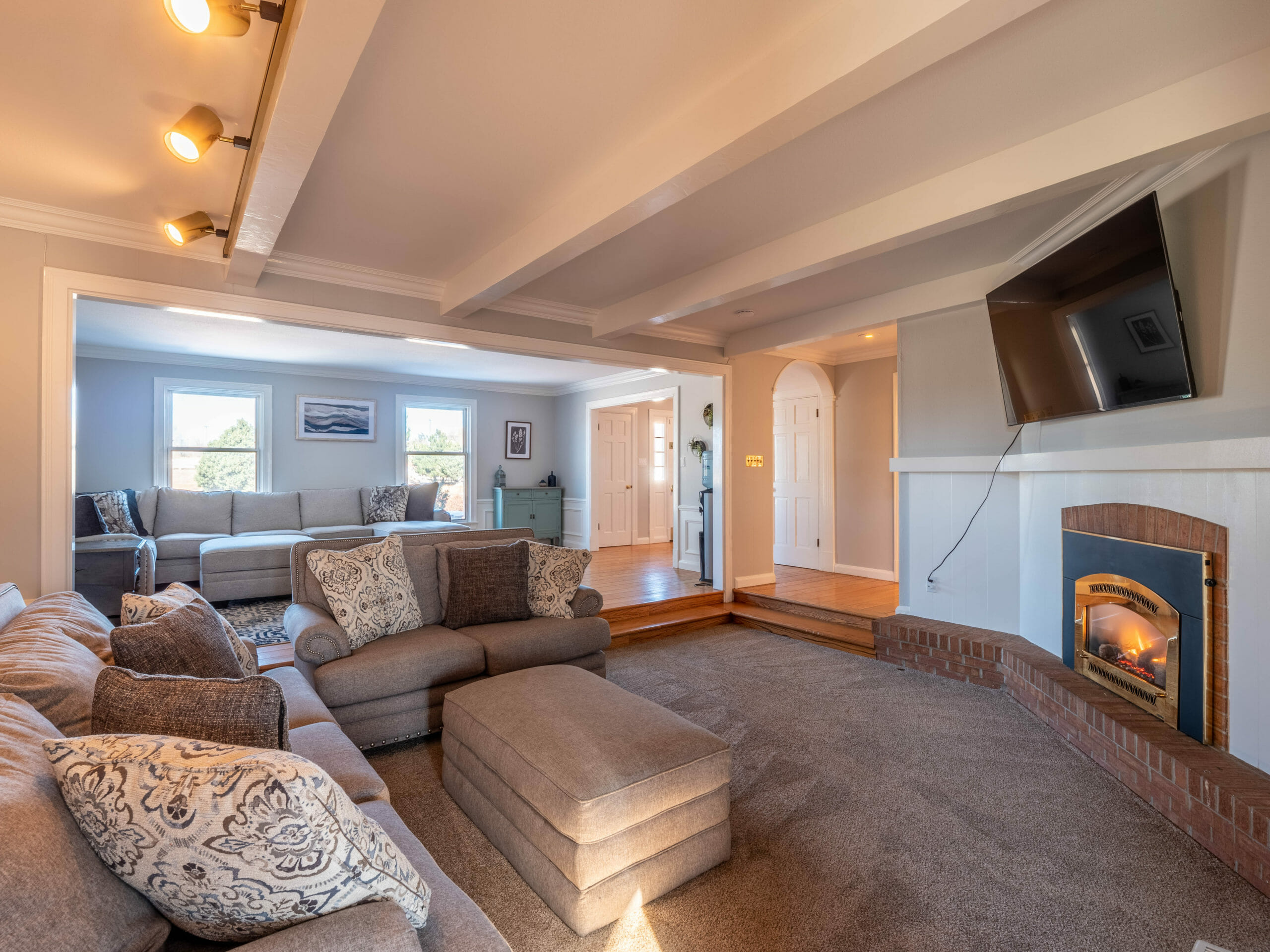 Carpeted lounge with sectional sofas and wall-mounted TV