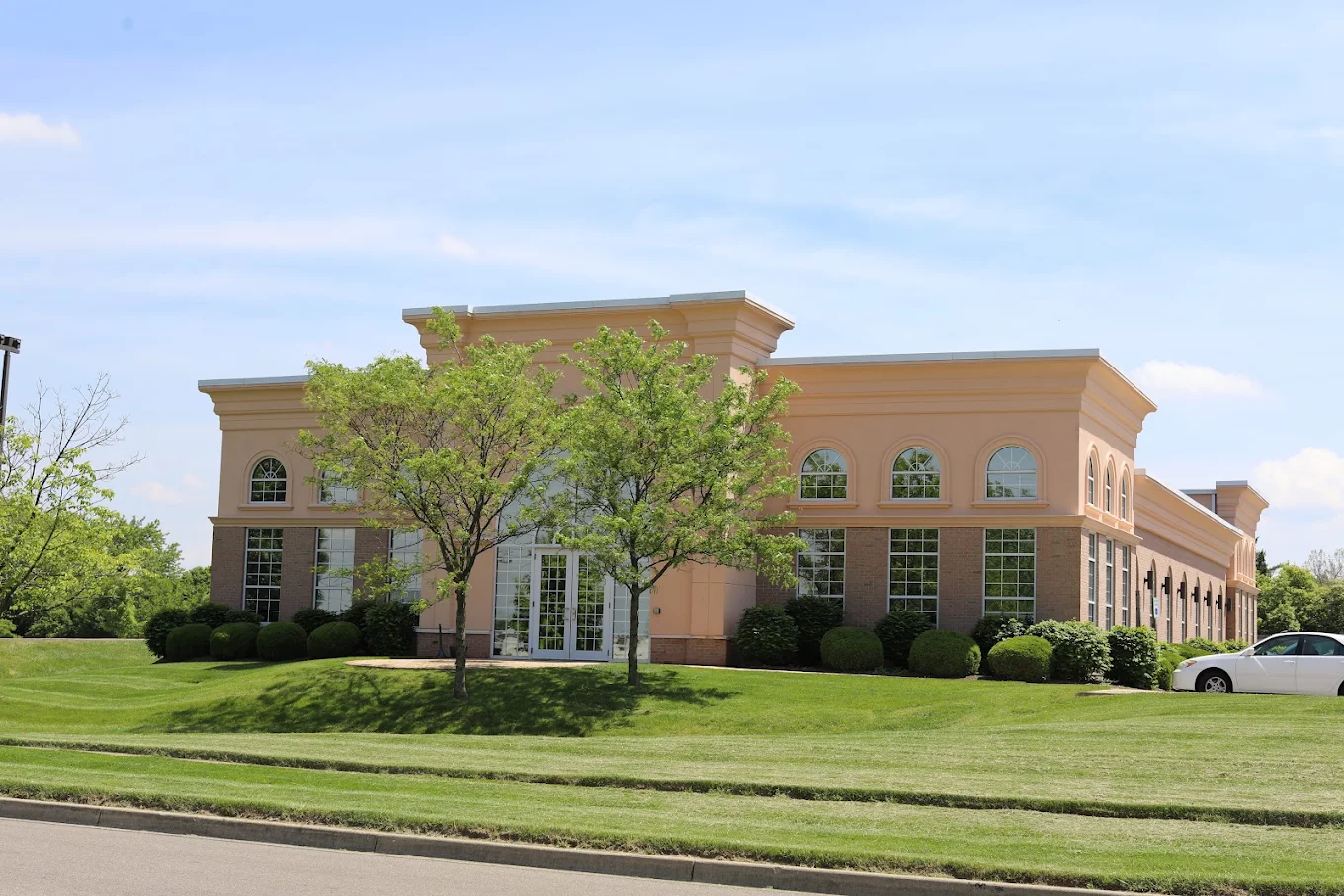 Wide exterior view of the BrightView Health Centerville treatment center with arched windows, trees, shrubs, and landscaped lawn