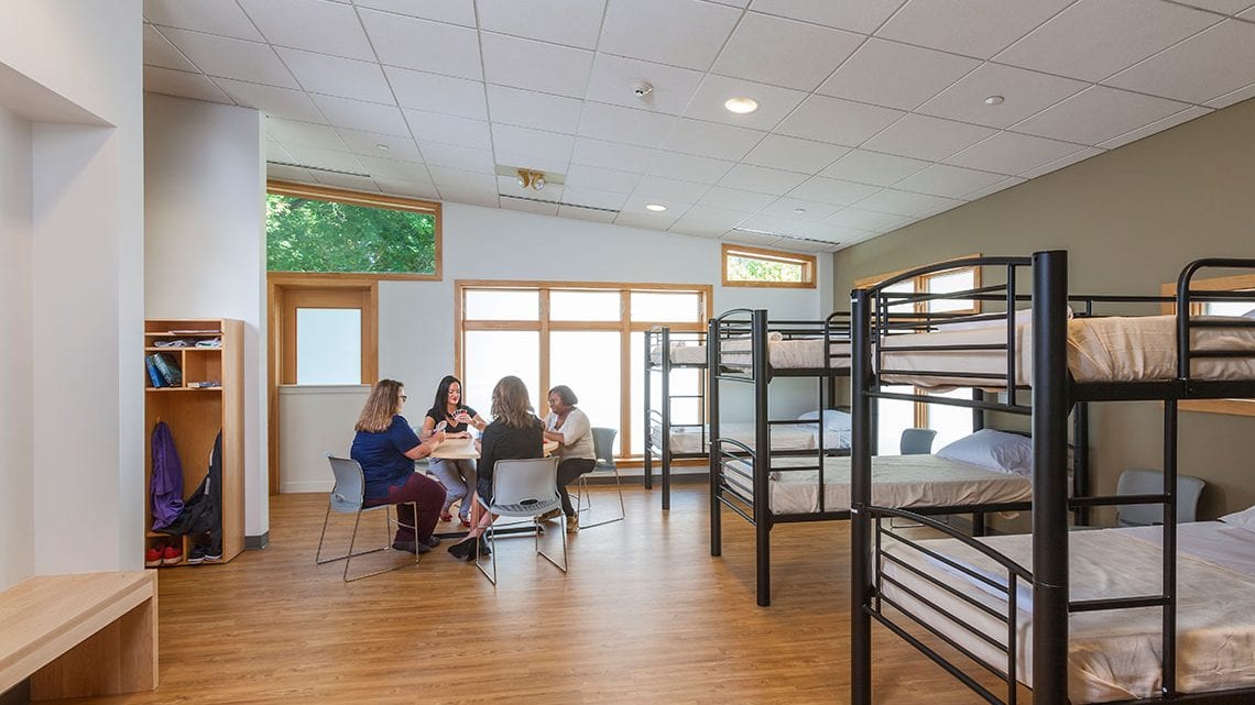 Dorm room with bunk beds and group seated at table