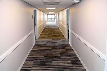 Long hallway with gray carpet and bright walls