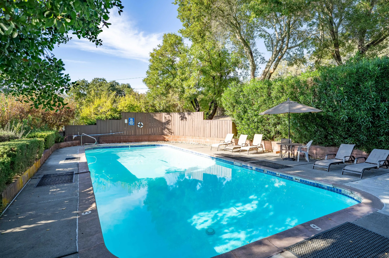 Outdoor swimming pool surrounded by trees and lounge chairs