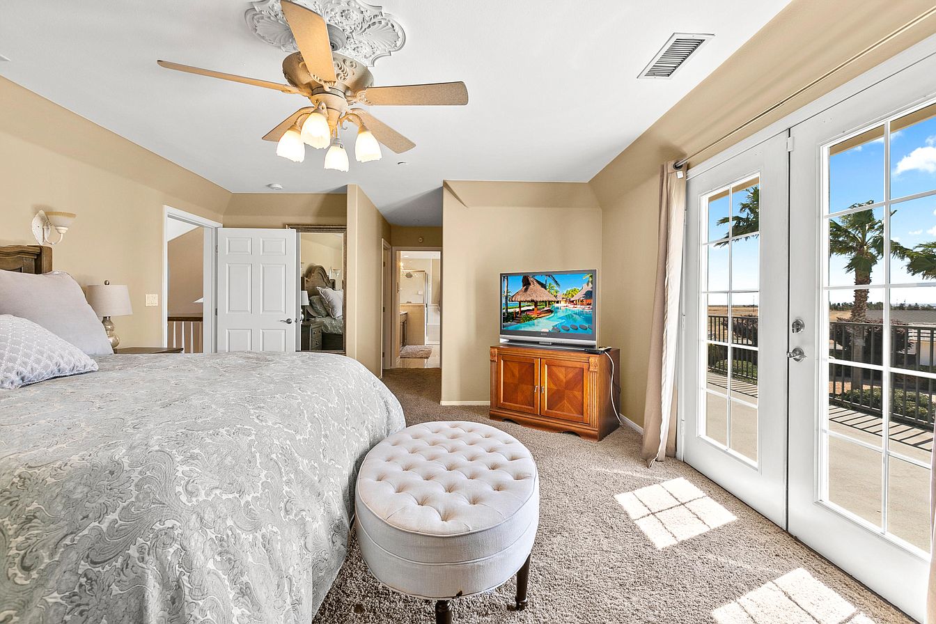 Sunlit bedroom with balcony doors and TV view