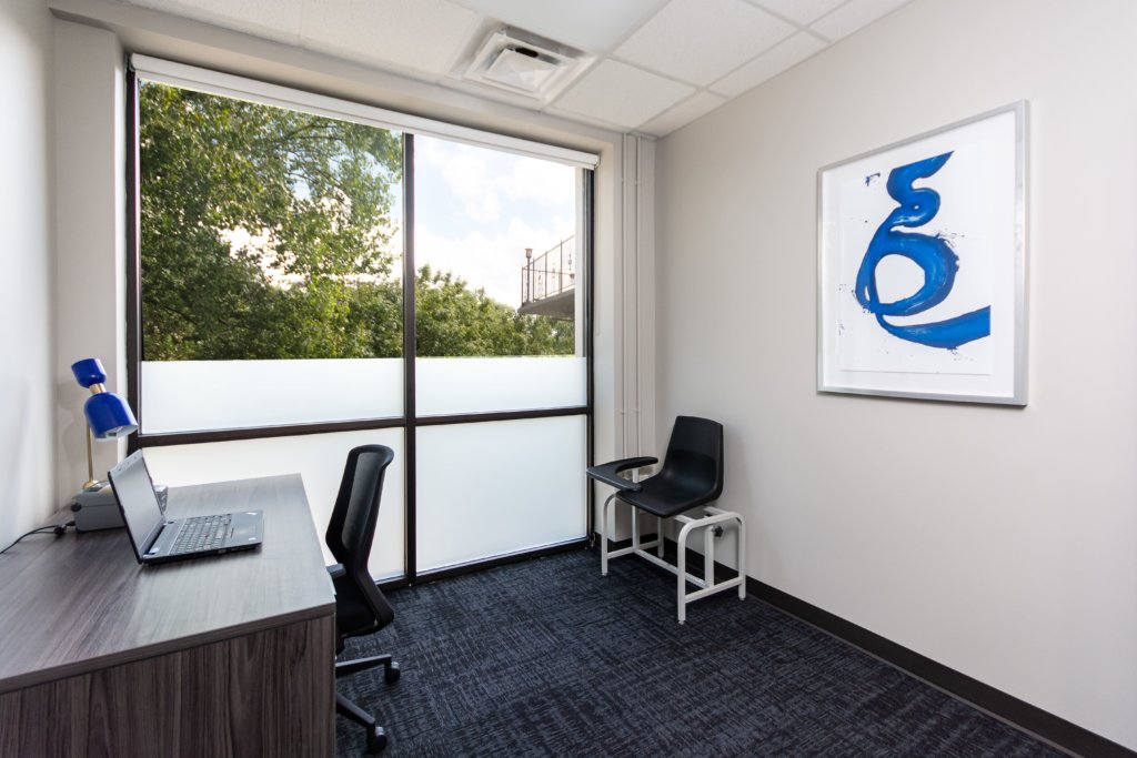 A private office with a desk, laptop, and a blue chair.