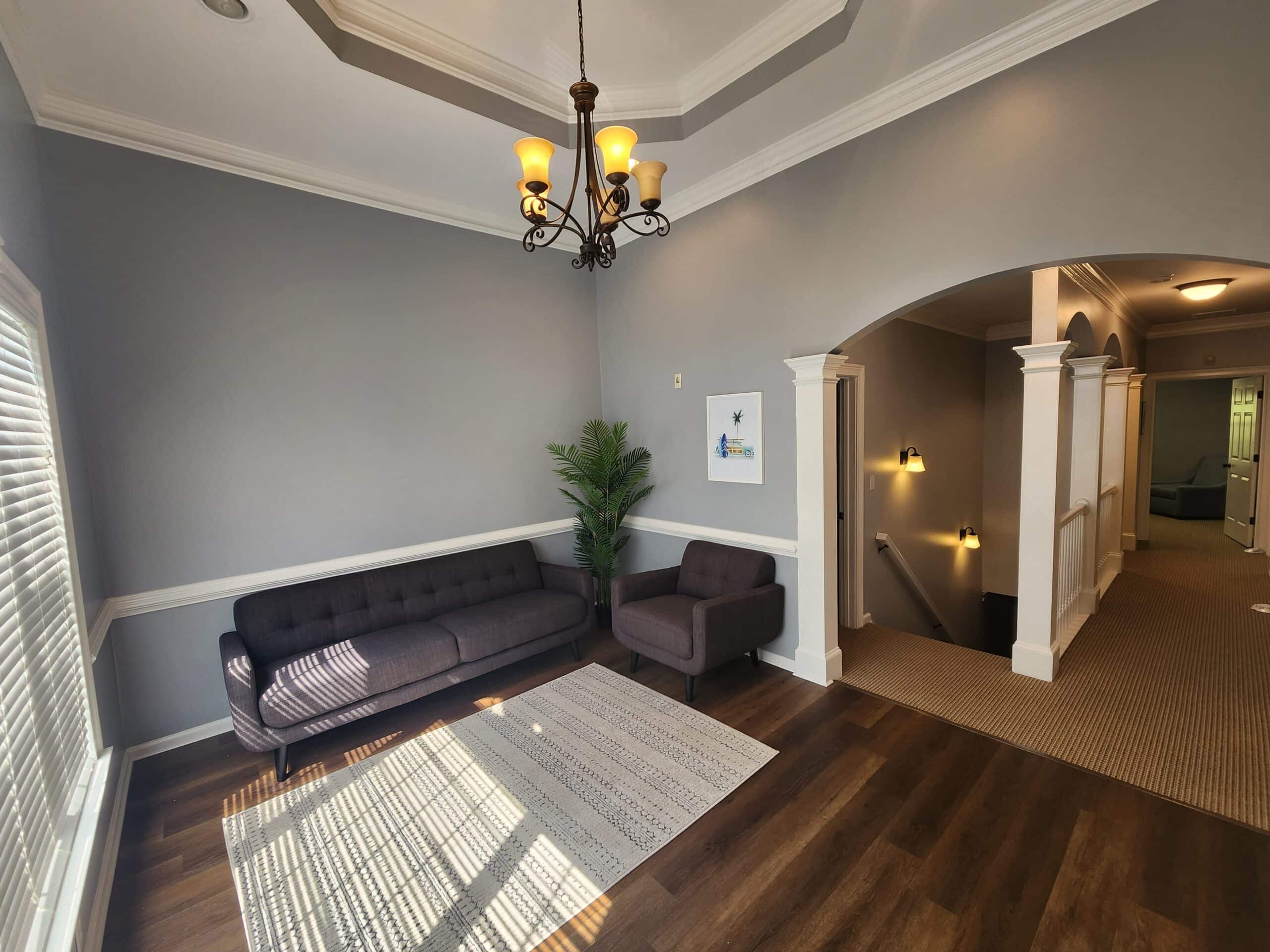 Lounge with gray sofa, armchair, rug, and overhead chandelier