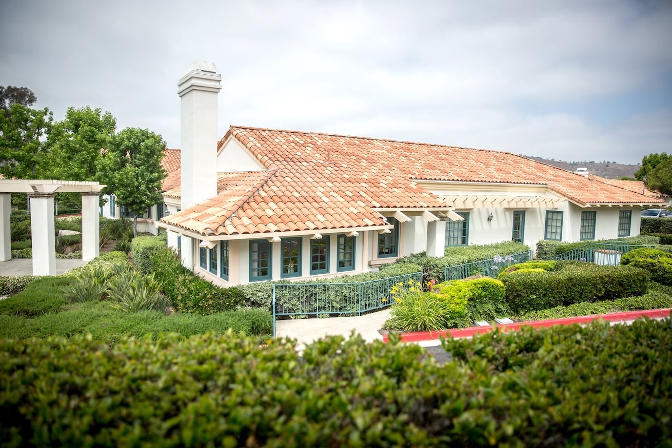 A rehab facility with a terracotta roof and lush landscaping.