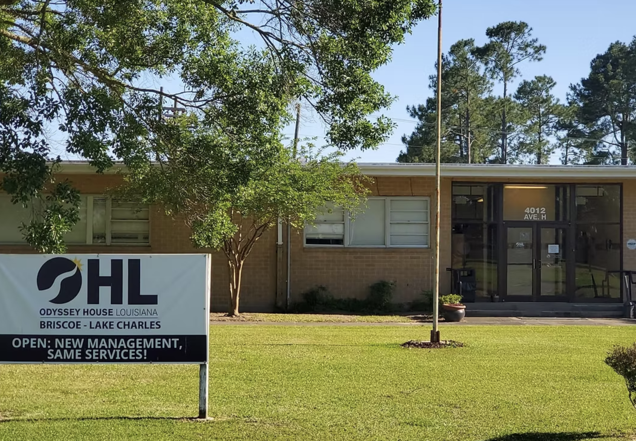 Brick building with glass entrance and Odyssey House lawn sign