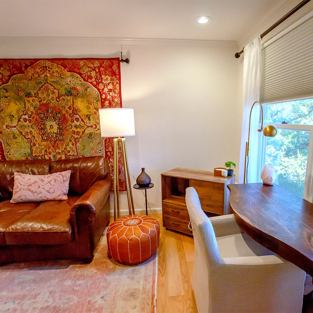 Therapy room with sofa, desk, and wall tapestry