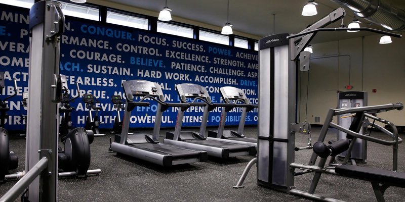 Modern fitness center with treadmills, weight machines, and motivational words on the wall, creating an energetic environment for workouts.