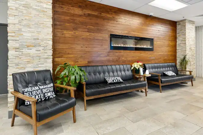 Lobby with black couches, wood accent wall, and fireplace