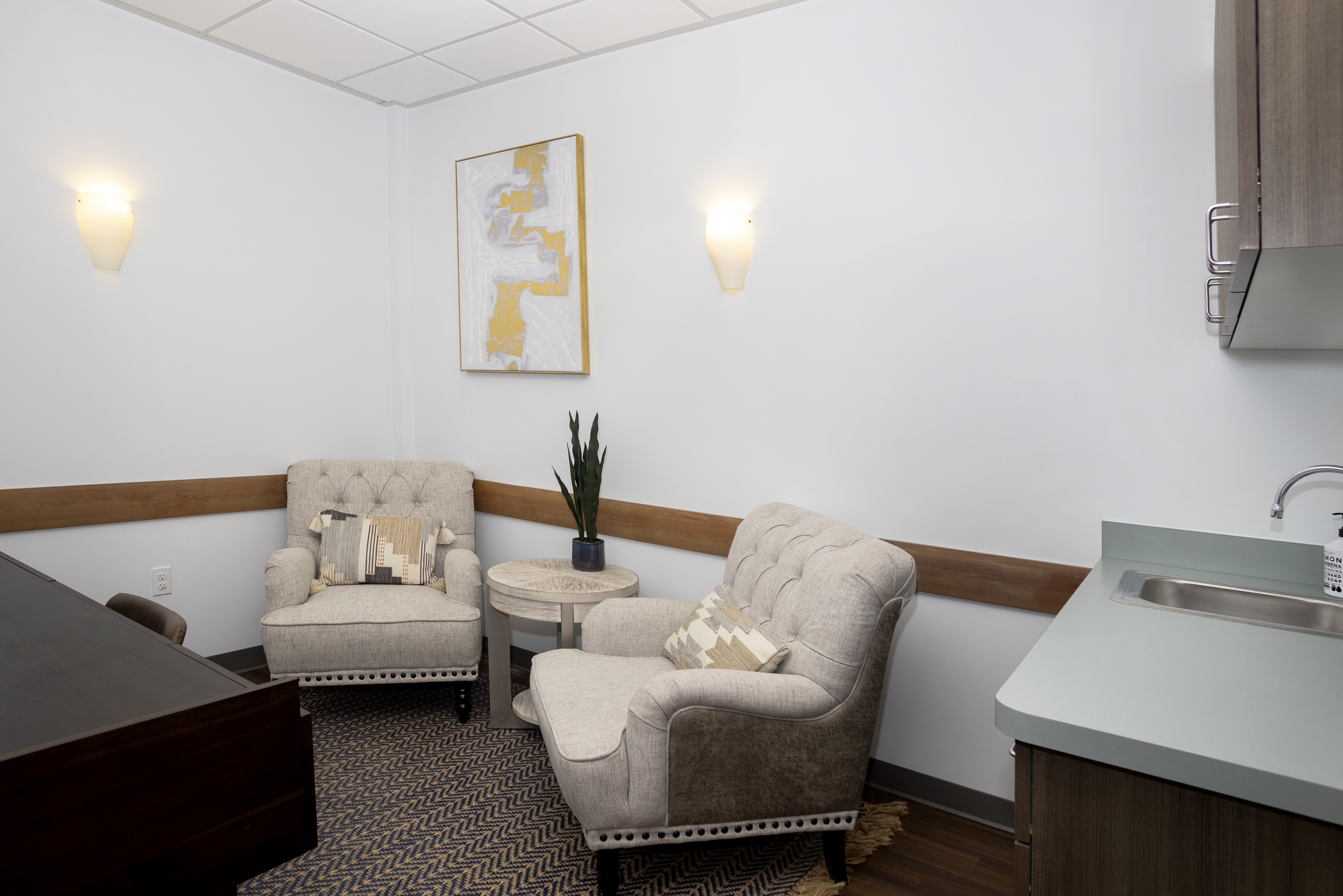 Two beige armchairs with pillows in a quiet therapy room
