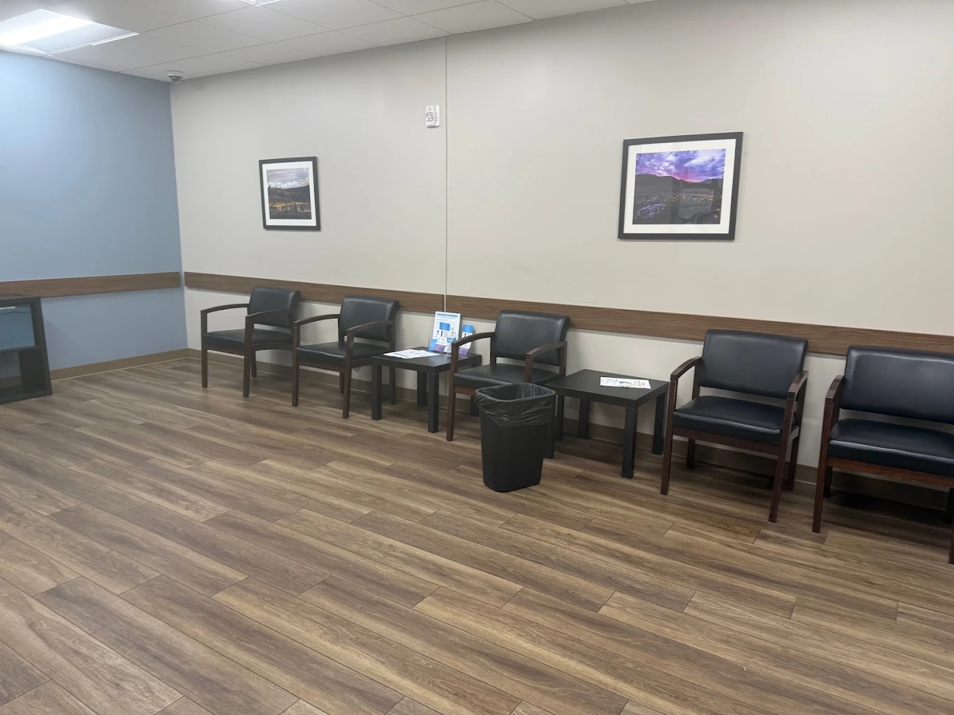 Waiting area with black chairs and framed landscape art