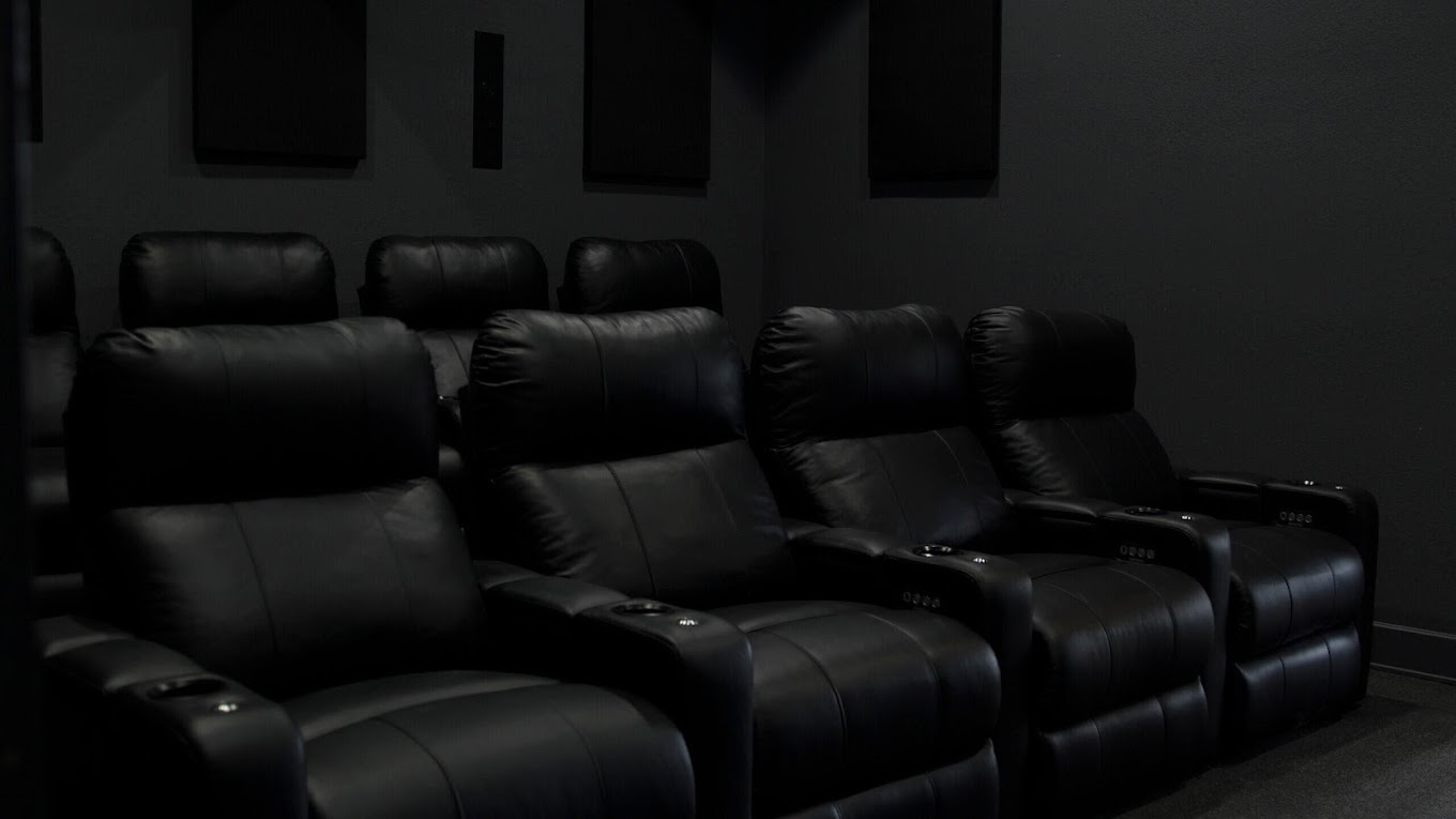 A dark home theater with black reclining chairs.