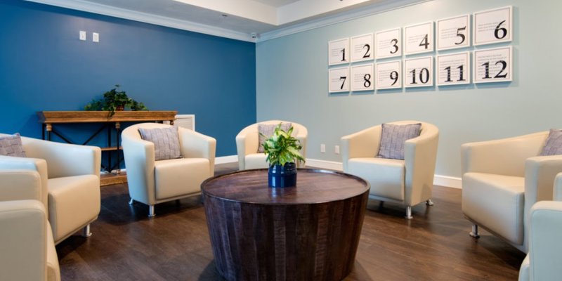 A modern and inviting meeting space with comfortable chairs arranged around a round wooden table, creating a welcoming environment for group discussions.