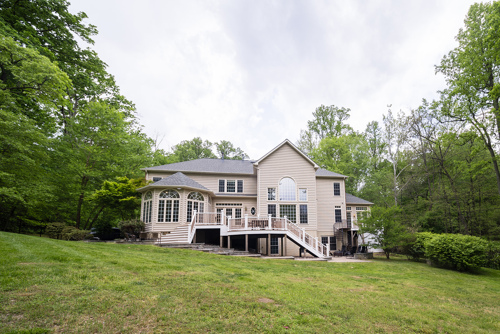 Rear view of large home with deck and wooded backdrop