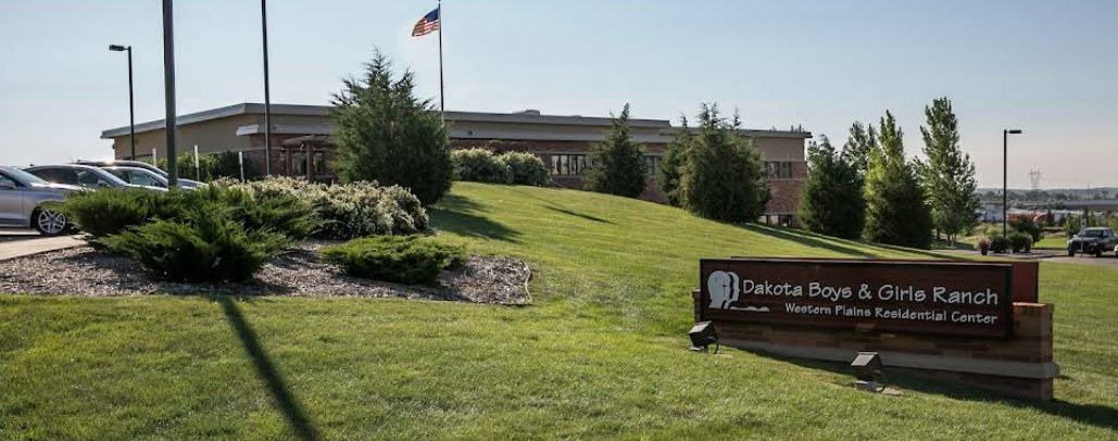 Building with American flag and sign on a grassy hill