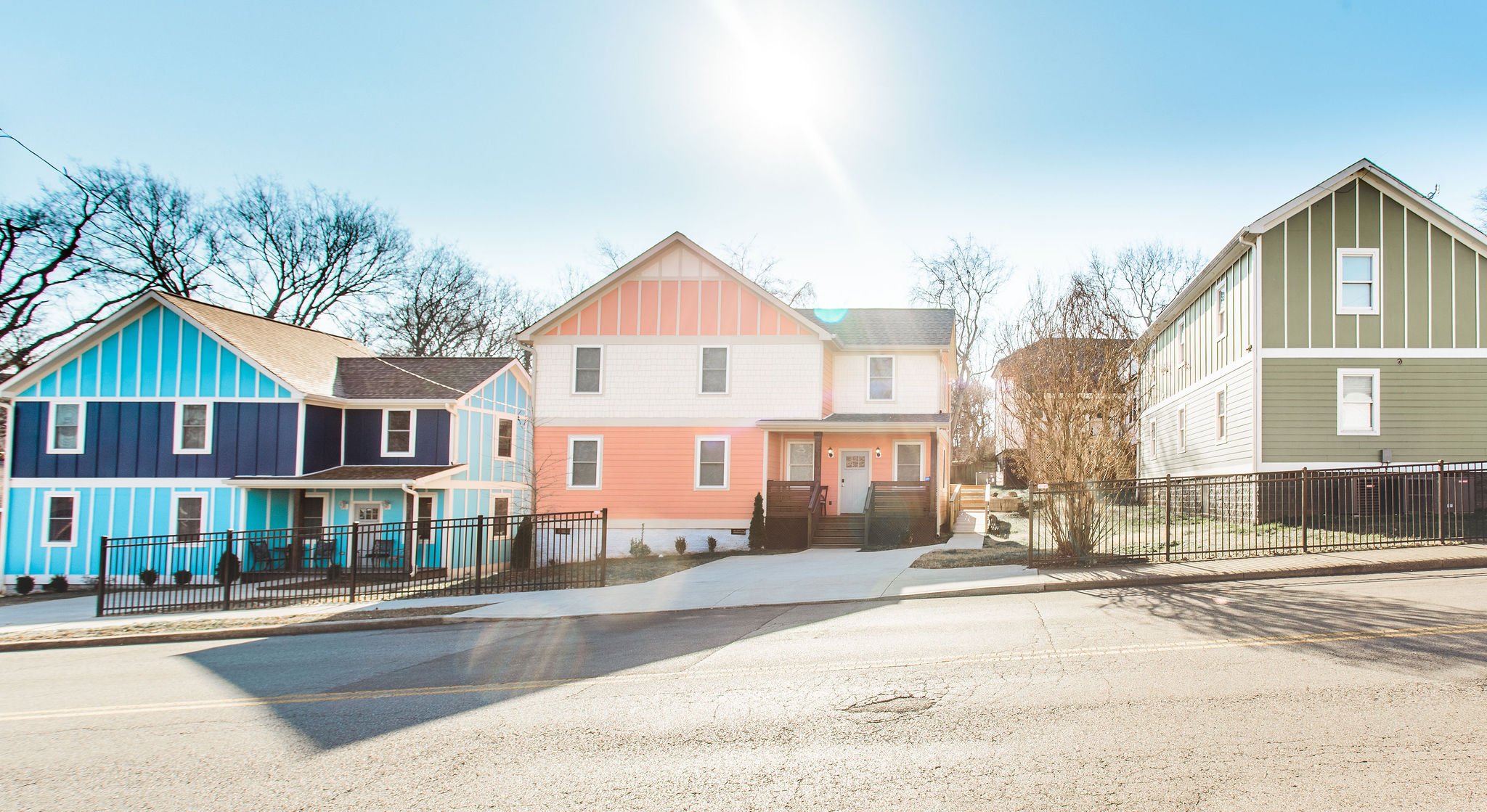 Colorful houses with fenced yards under bright sun