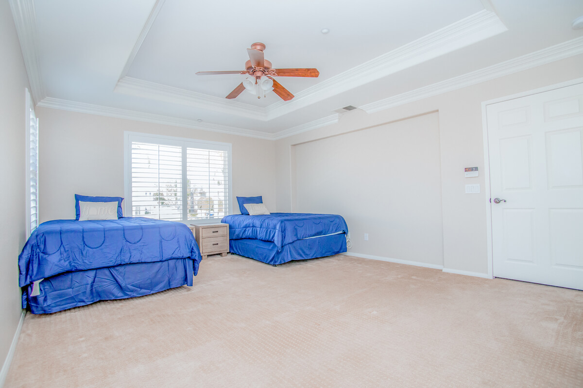 Spacious bedroom with two twin beds and ceiling fan