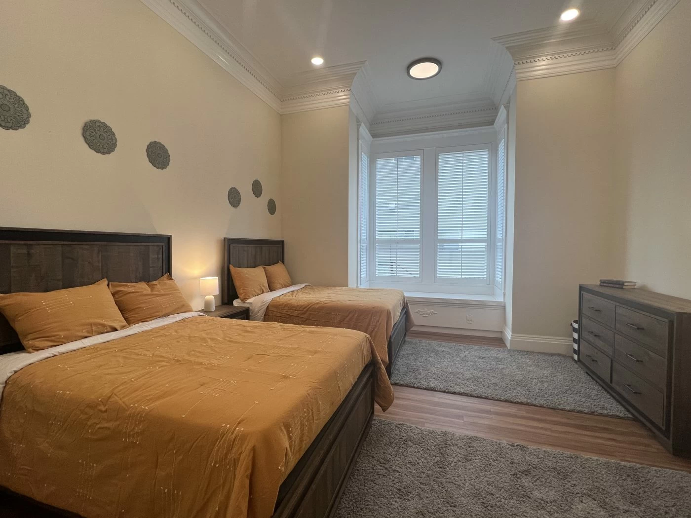 Bedroom with two beds, dresser, and large window with natural light