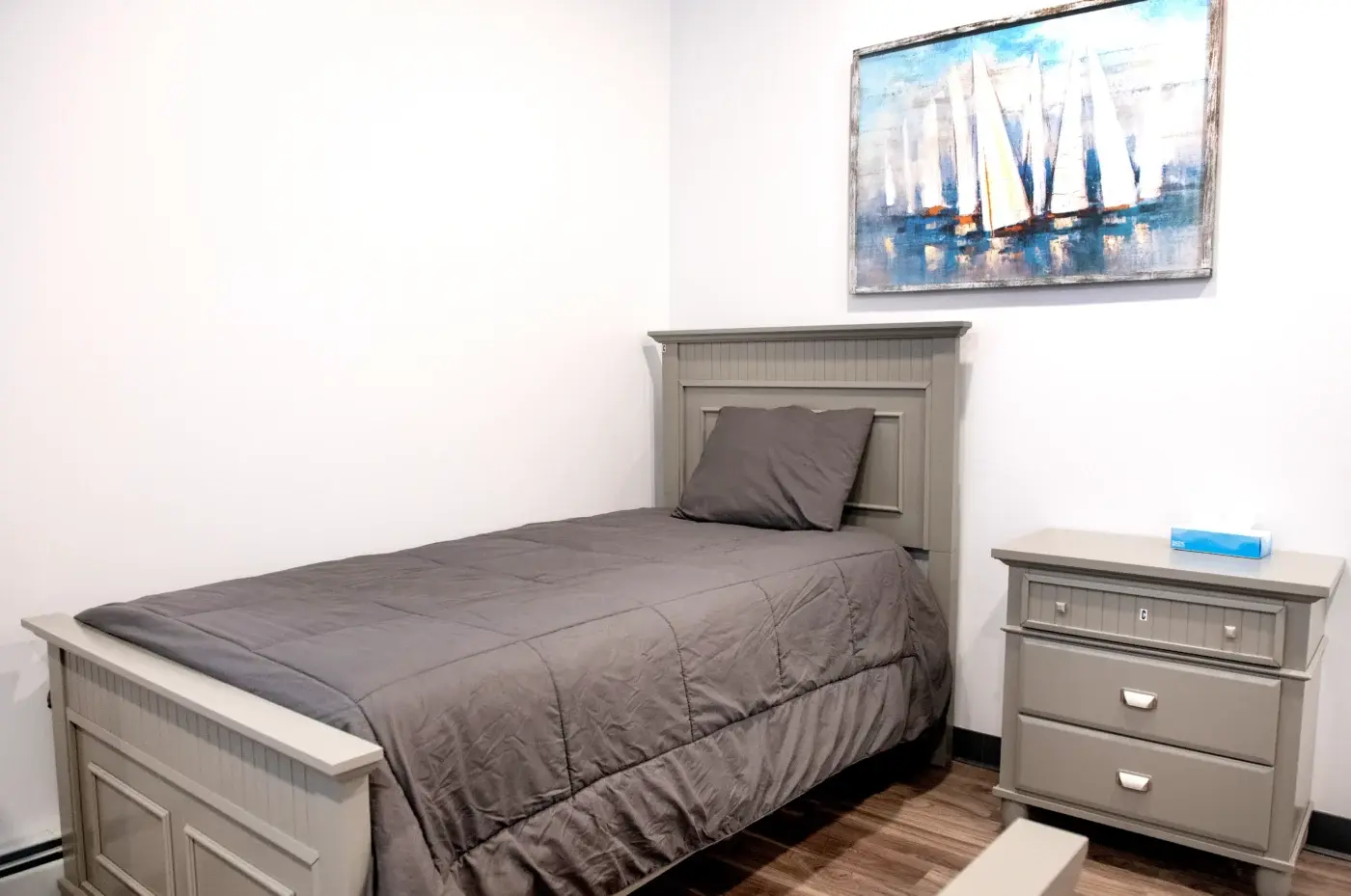 Room with a gray twin bed and nightstand