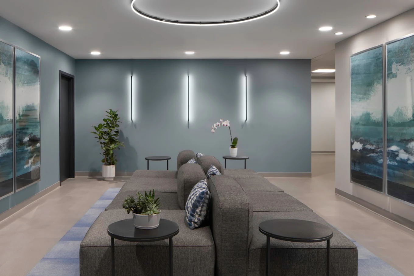 Modern sitting area with sofa, tables, plants, and wall art