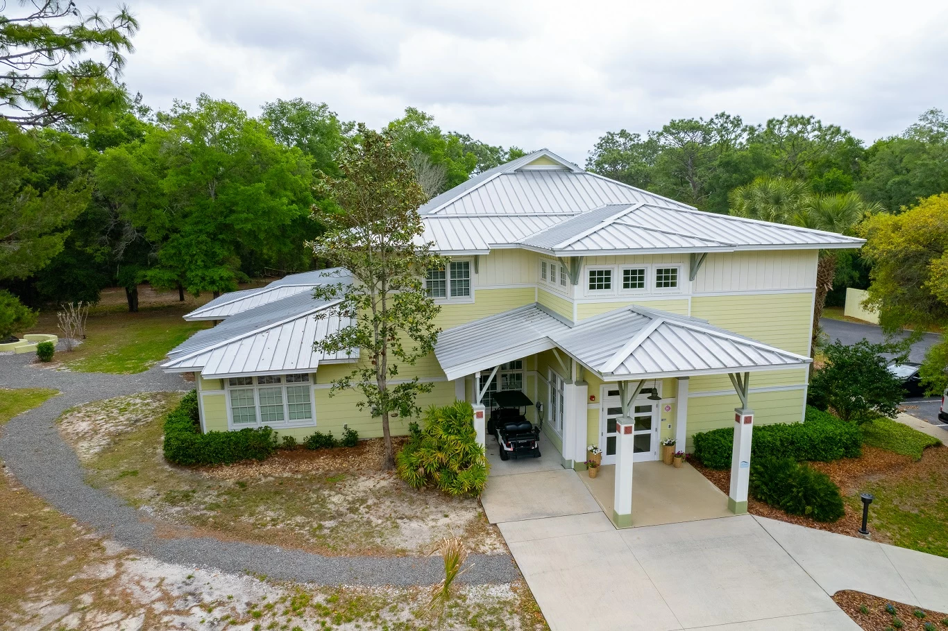 Light yellow treatment facility building with covered entrance, landscaped walkway, and surrounding greenery