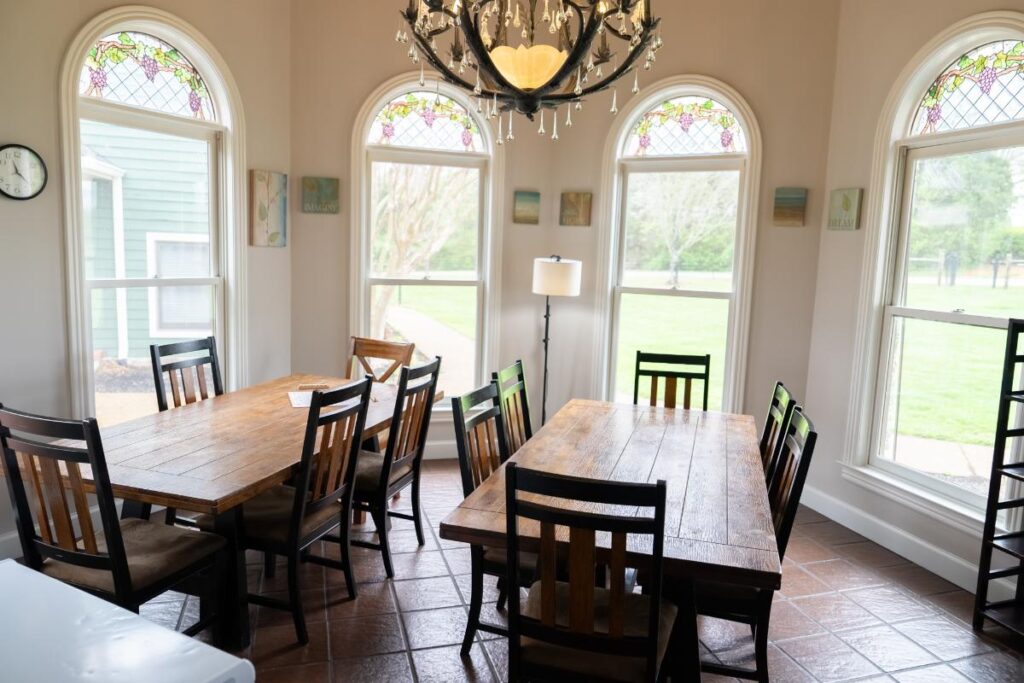 Rustic dining room with stained glass windows and two wooden tables with chairs