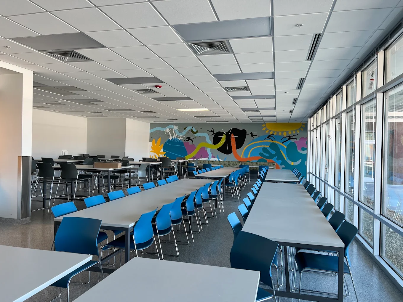 Spacious dining area with blue chairs and long tables