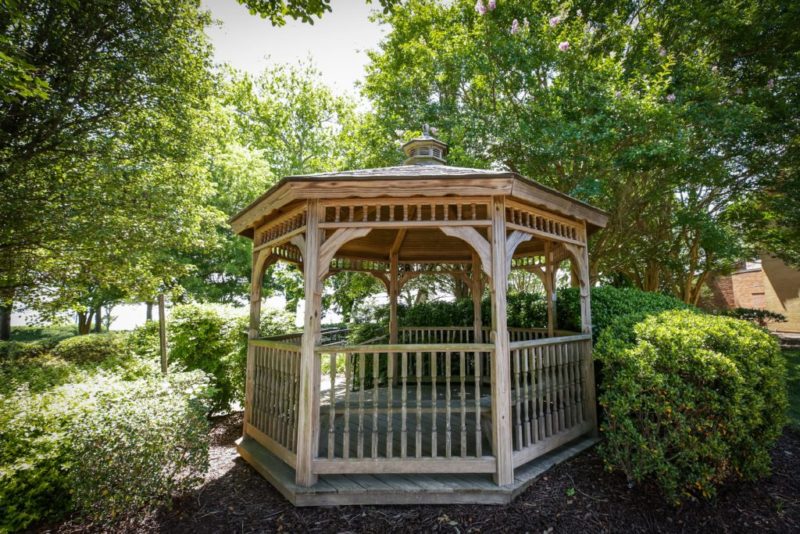 Wooden gazebo surrounded by trees and bushes