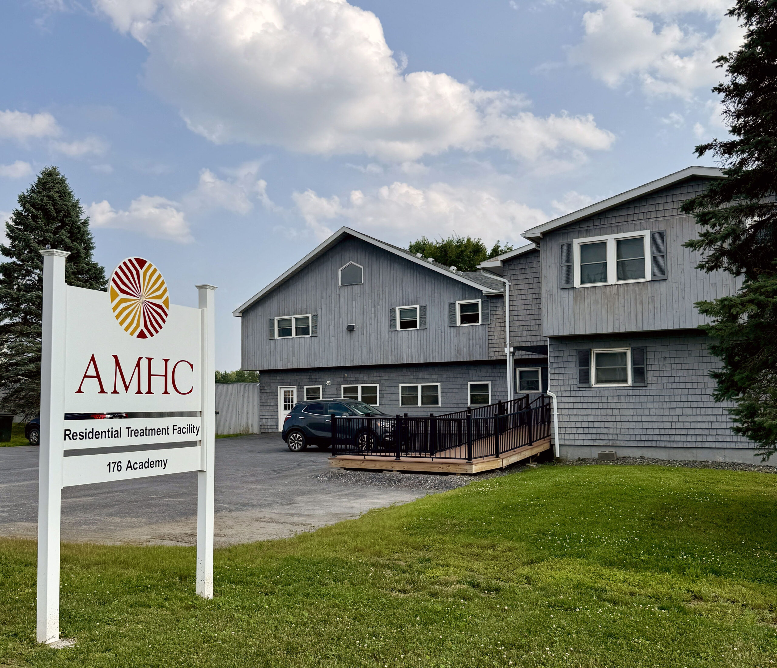 AMHC residential treatment building with sign and parking area.