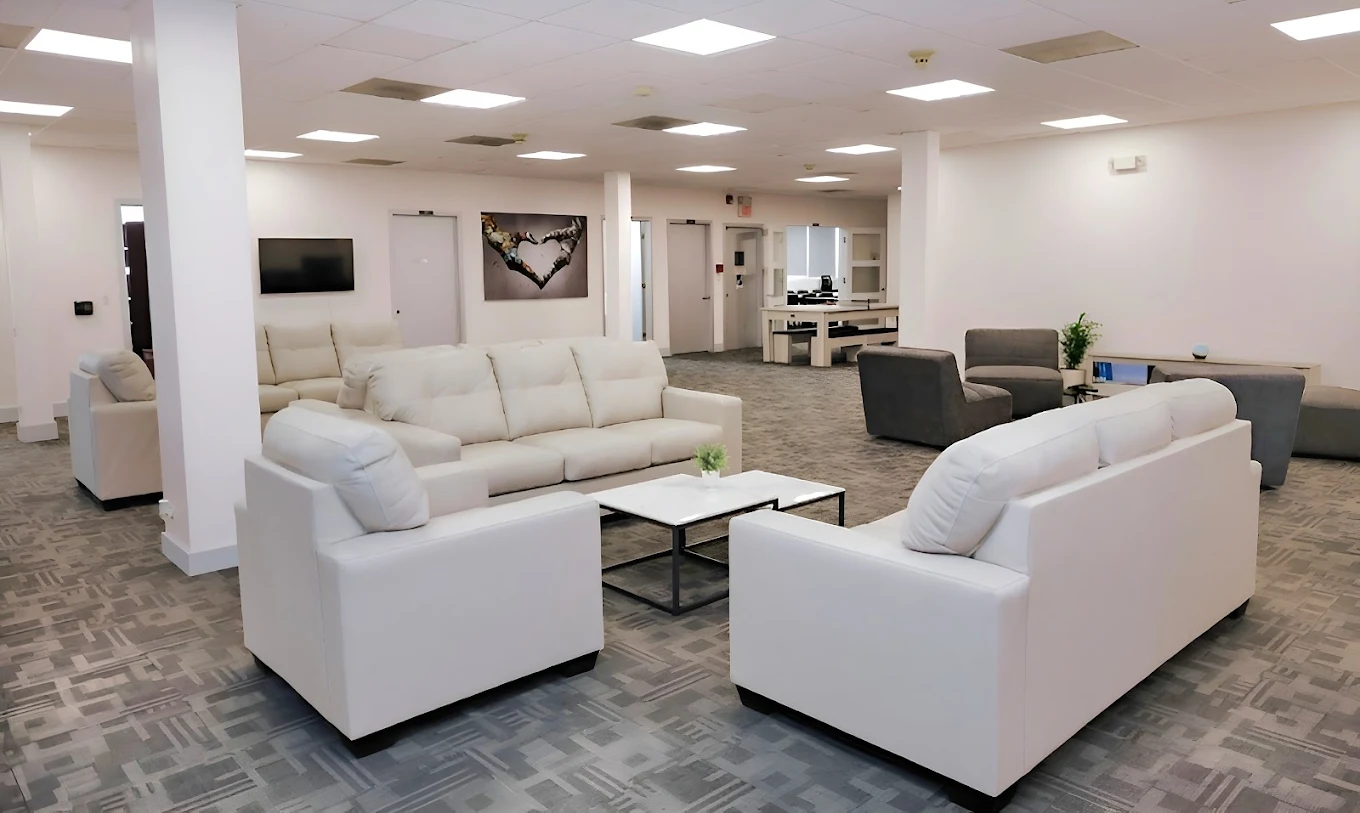 Spacious living area with white sofas, chairs, and coffee tables