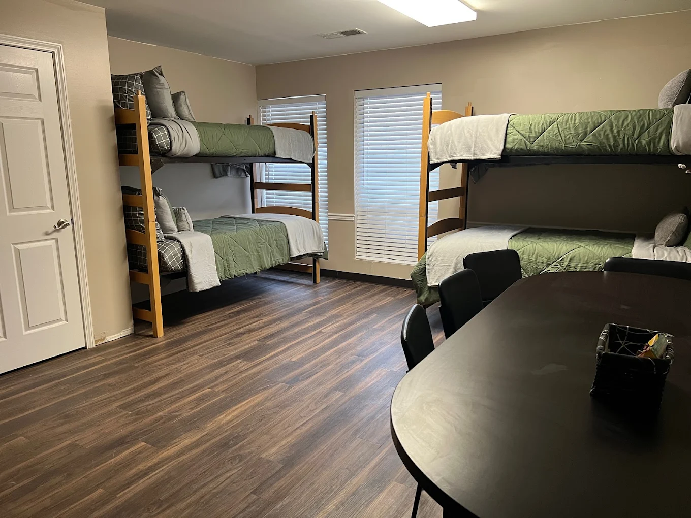Shared bedroom with two sets of wooden bunk beds, a dining-style table with chairs, and hardwood flooring